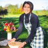 a woman in an apron is holding a basket