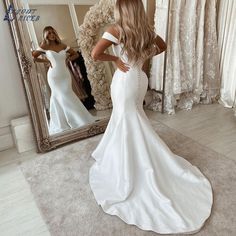 a woman standing in front of a mirror wearing a white dress and looking at her reflection