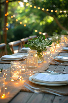 a table set for dinner with mason jars and lights on the table, along with plates and napkins