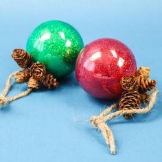 two christmas ornaments on a blue background with pine cones and twined twine around them