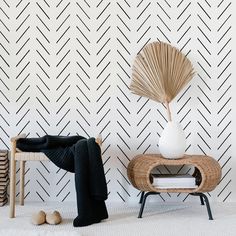 a white vase sitting on top of a wooden table next to a chair and ottoman