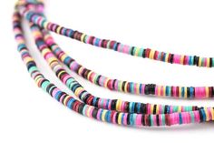 multicolored striped glass beads are arranged on a white surface with one bead in the middle