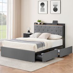 a bed with two drawers underneath it in a living room next to a large window