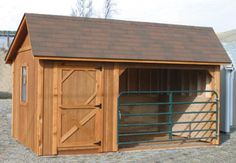 a small wooden shed with a brown roof and gated in area next to it