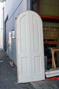 an open white door sitting in front of a building