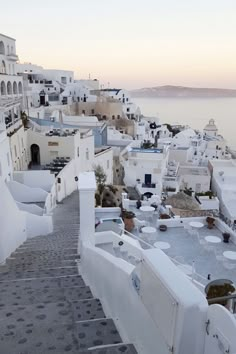 an alley way leading to the ocean with white buildings on either side