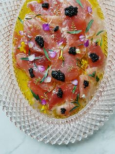 a glass plate topped with watermelon and blackberries