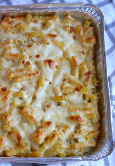 a casserole dish with cheese and pasta in it on a checkered table cloth