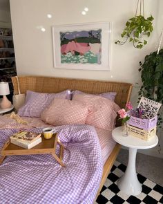 a bed sitting next to a table with books on it and a potted plant