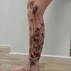 a woman's leg with an owl and flowers tattoo on it