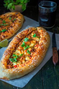 two large pizzas sitting on top of a table next to a knife and fork