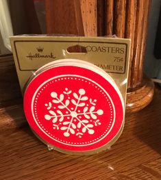 a red and white coaster sitting on top of a wooden table