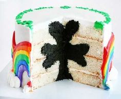 there is a cake with white frosting and rainbow decorations on it, cut in half