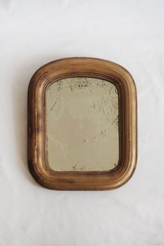 an old mirror sitting on top of a white sheet