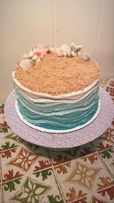 there is a cake that has shells on it and sand in the top layer, along with seashells