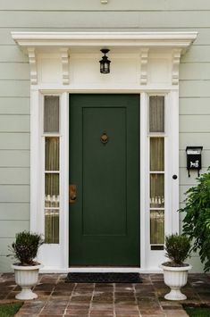 a green front door with two planters on either side