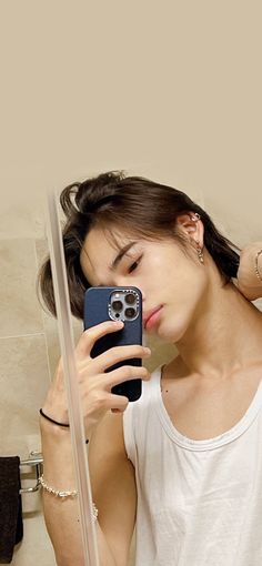 a woman taking a selfie in front of a bathroom mirror with her cell phone