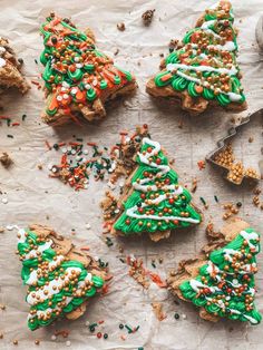 christmas cookies decorated with sprinkles and frosting are on a piece of parchment paper