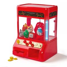 a red toy machine with stuffed animals in it's display case and some gold coins on the floor