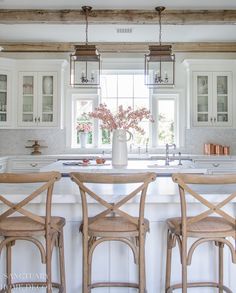 a kitchen with white cabinets and wooden chairs