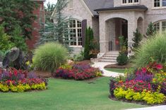 a house with flowers in front of it and landscaping around the entrance to the home