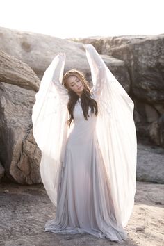 a woman in a white dress is posing with her arms spread out and wings outstretched