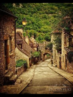 an alley way with stone buildings and trees on the hill in the backgroud