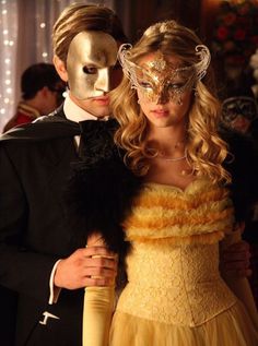 a man in a tuxedo standing next to a woman with a mask on