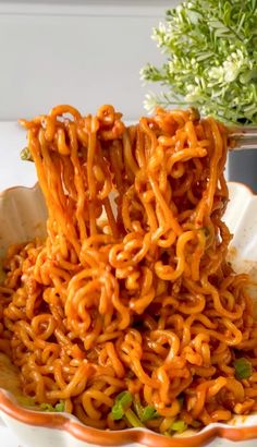 a bowl full of noodles with chopsticks sticking out of the top and sauce in the middle