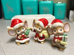 three figurines of mice in santa's hats and holding presents on a counter