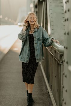 a woman standing on the side of a bridge talking on a cell phone and smiling