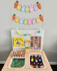 a wooden table topped with lots of cake and candies next to a happy easter banner