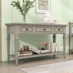 a grey console table with drawers and books on it in a room that has green walls