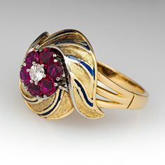 This elegant circa 1940s features engraved details with blue enameling. The ring is centered with one (1), prong set, round brilliant cut diamond, bordered with six (6), prong set, round mixed cut natural rubies. The ring measures 17.8mm at the top, rises 9.6mm above the finger, tapering to 2.3mm wide and 1.1mm thick at the base of the shank. This ring is currently a size 10. Heirloom Enamel Jewelry For Formal Occasions, Art Deco Yellow Gold Enamel Ring For Formal Occasions, Art Deco Formal Yellow Gold Enamel Ring, Formal Yellow Gold Art Deco Enamel Ring, Formal Art Deco Yellow Gold Enamel Ring, Vintage Diamond Enamel Round Ring, Vintage Round Diamond Enamel Ring, Formal Art Deco Ruby Ring In Yellow Gold, Art Deco Yellow Gold Ruby Ring For Formal Events