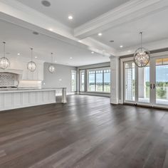 an empty living room with wood floors and large windows