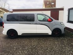 a white van parked in front of a building with black rims and red brake pads