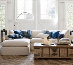 a living room filled with lots of furniture and pillows on top of a table next to a window