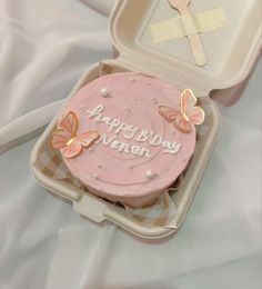 a pink cake in a plastic container with butterflies on it and the words happy birthday nannen