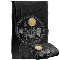 a black blanket and pillow set with a castle on the hill in front of a full moon