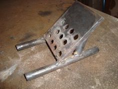 a metal grate sitting on top of a table next to a piece of wood