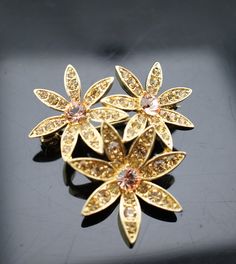 This is the perfect option for those who like cool, unique jewelry and the luxury, shine of gold and pink. This brooch is well made, cute and/or elegant in design, and very desirable. The brooch has shape of 3 flowers. The brooch is decorated with pink, clear cz. The clasp is in good working condition. ♥ Age/era: Circa before 2000s. ♥ There is a hallmark.LC. ♥ The brooch is about 1 7/8'' X 1 6/8''. Every one interested in the jewelry should remember that he or she must like their jewelry- not ju Gold Flower-shaped Brooch For Gift, Gold Flower Shaped Brooch As Gift, Gold Flower-shaped Brooches For Gifts, Gold Flower Shaped Brooch For Gift, Rose Gold Flower Brooches As Gift, Black And Gold Aesthetic, Art Deco Jewelry Vintage, Pink Art Deco, Vintage Jewelry Art