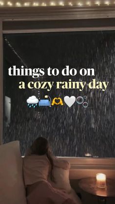 a woman sitting on a couch in front of a window with the words things to do on a cozy rainy day