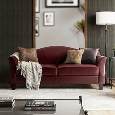 a living room with a red couch and two pillows on the armrests in front of a mirror