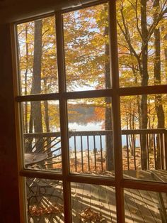 an open window looking out onto a lake in the fall with leaves on the ground