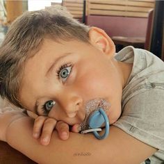 a young boy laying on top of a table with a pacifier in his mouth