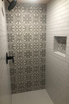 a walk in shower sitting next to a white tiled wall and floor covered in tile