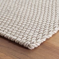 a close up view of a white rug on a wooden floor with a wood floor