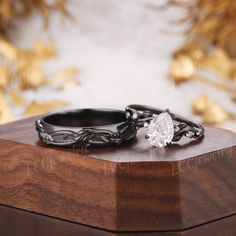 two wedding rings sitting on top of a wooden box with gold leaves in the background