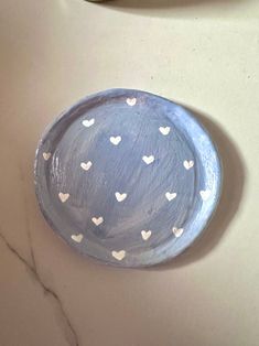 a blue plate with white hearts on it sitting on a marble counter top next to a bowl