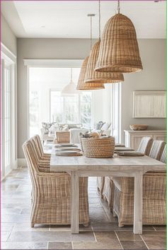 a dining room table with wicker chairs and baskets hanging from it's ceiling